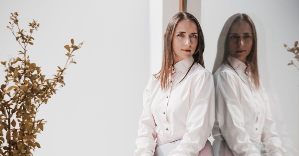 How Is Your Imposter Showing Up? | Signs of Imposter Syndrome Professional woman reflected in a glass wall, symbolising self-doubt and the inner critic behind imposter syndrome.