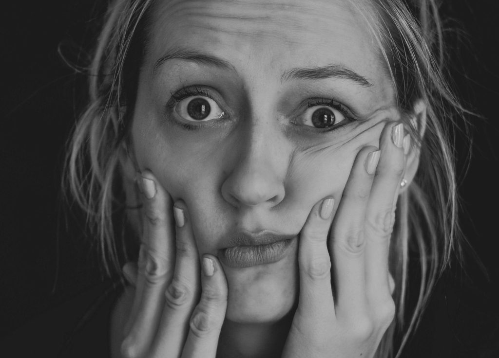 Close-up of a woman holding her face in frustration, representing the pressure and gender bias often experienced by executive women leaders.