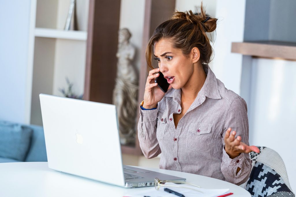 Executive woman stressed by urgent work request on phone Executive woman reacting to an urgent request while on the phone, representing the overwhelm and boundary challenges addressed in the blog for executive women
