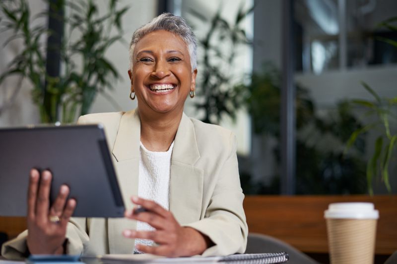 Executive Menopause Coach Mature professional woman smiling calmly in the workplace, representing executive menopause coaching