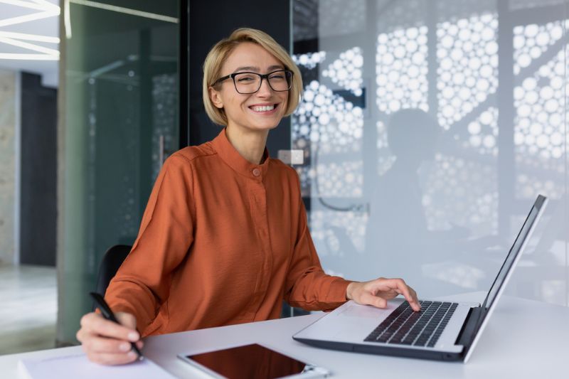 Female Leadership Coaching Focused businesswoman working on laptop in bright workspace, representing female leadership coaching