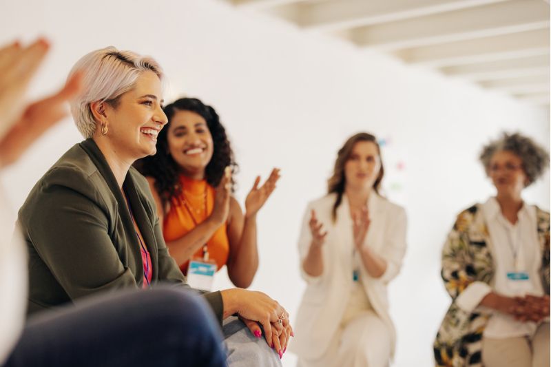 Executive women in a small group coaching session, sharing laughter and support in a safe space.