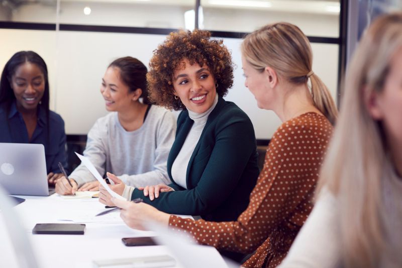 Female coach facilitating an executive group coaching session with engaged women leaders.