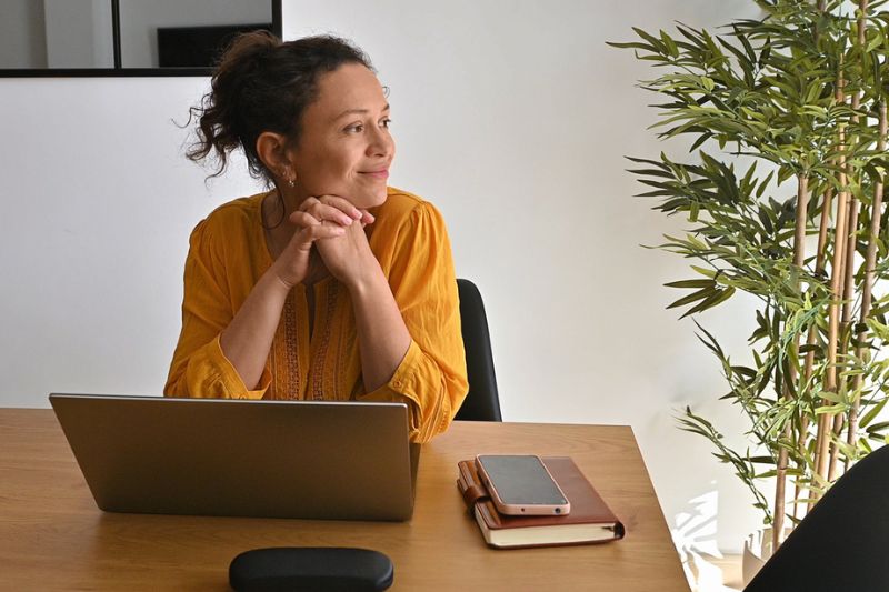 Professional woman taking a quiet moment at her desk, using mindfulness and breathing techniques to find calm and focus.