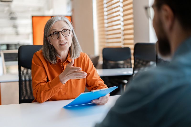Professional woman leading a focused discussion with a team member in a modern office, symbolising collaboration and high-performing team leadership.