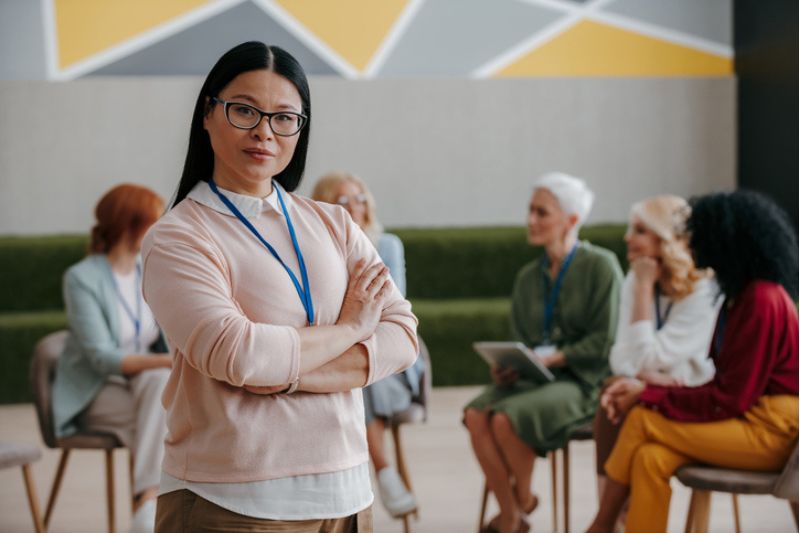 Confident woman with a coaching group in discussion, blending individual and group development.