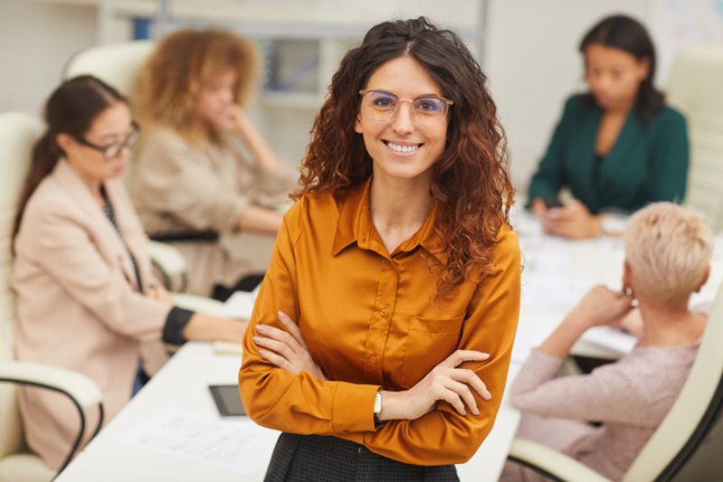 Female leader with team in background, focusing on implementing new leadership behaviours.