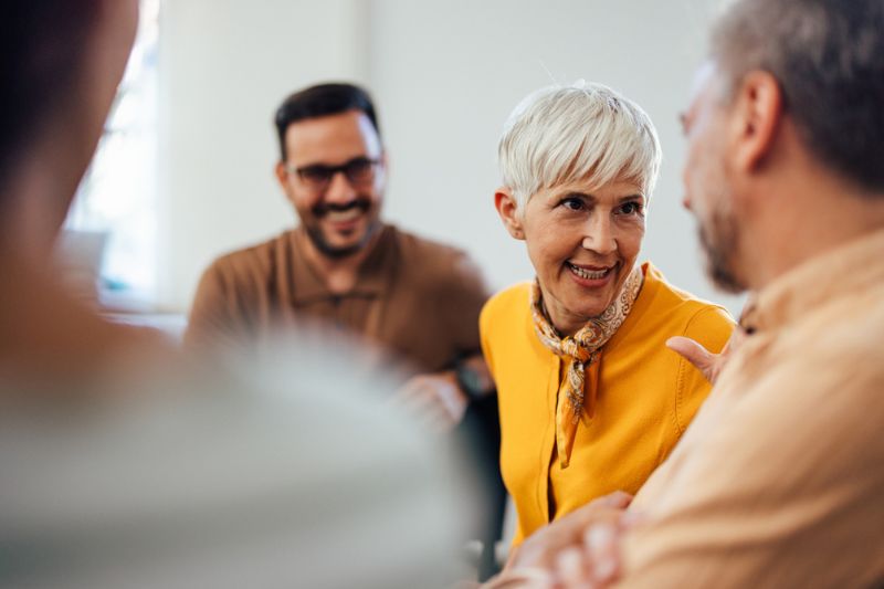 Mature professional woman engaging in a positive conversation with colleagues, representing mentoring, sponsorship, and leadership development.