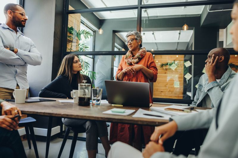 Confident leader addressing a diverse team in a modern office, symbolising resilience, adaptability, and effective change management.